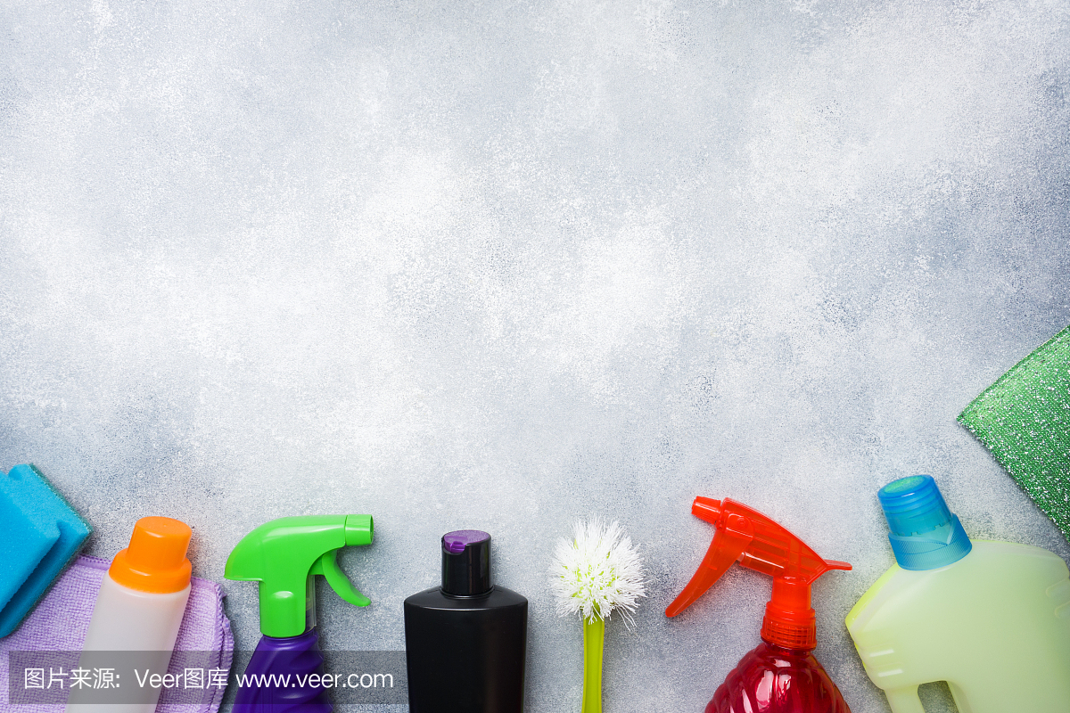 瓶子與洗滌劑,刷子和海綿在混凝土背景。色彩鮮艷的清潔產品。家庭清潔的概念。俯視圖,復制空間。